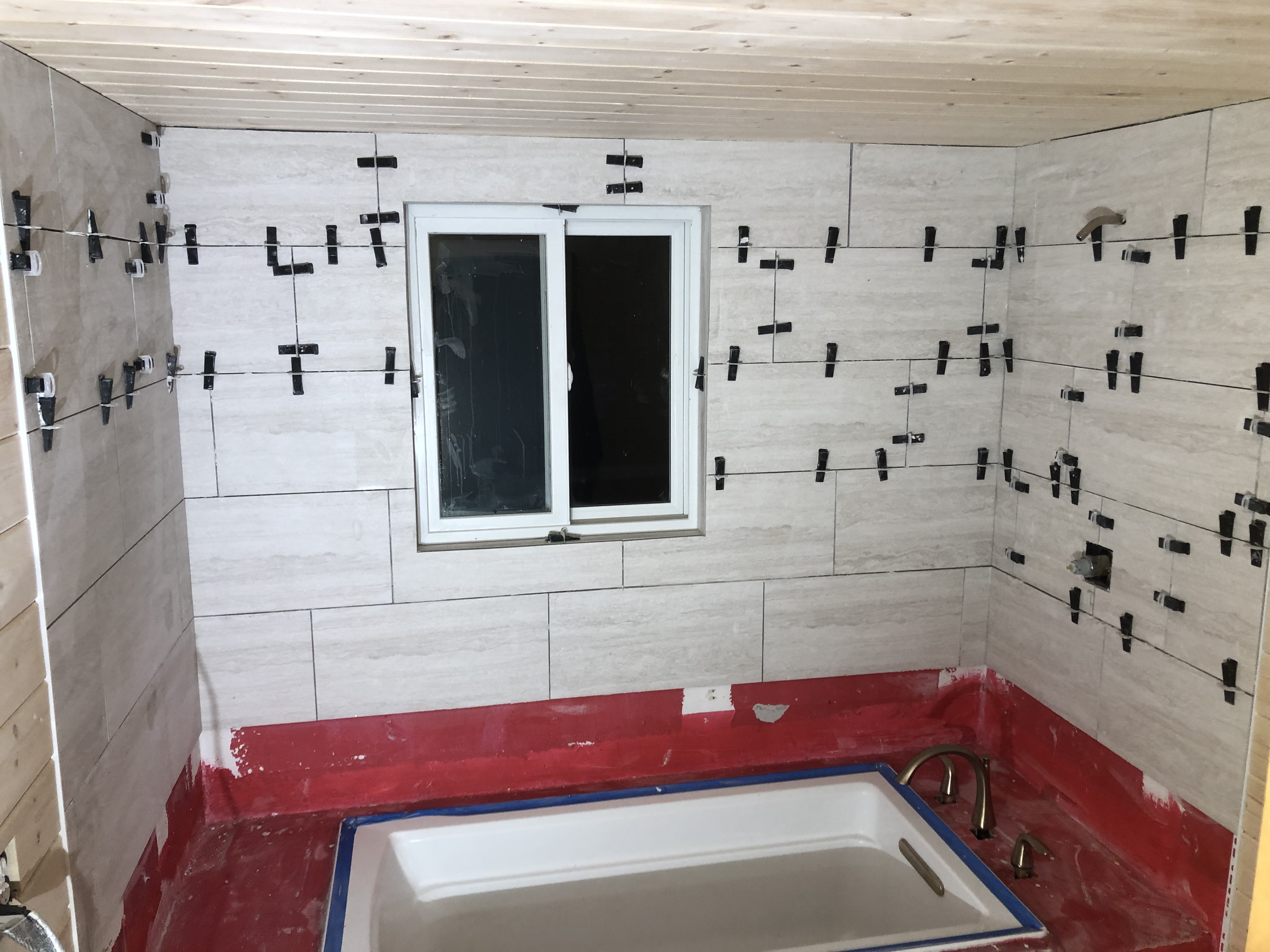 Bathtub walls being tiled with spacers